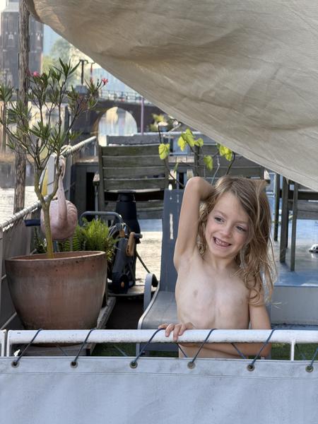 A young child poses under a canopy in a backyard setting